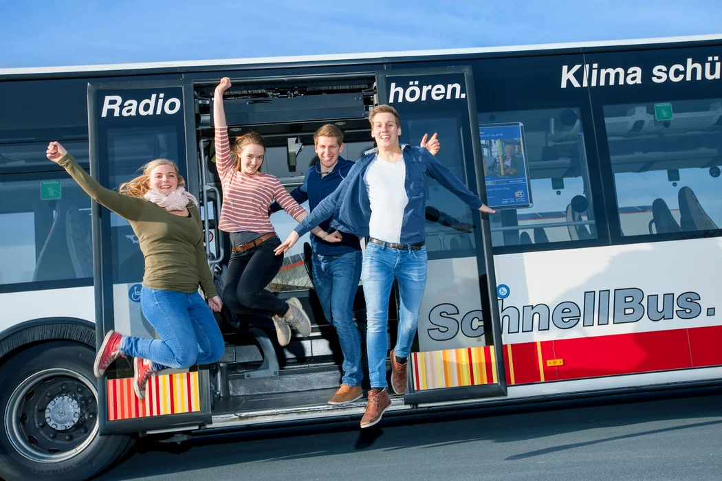 Menschen springen freudig aus einem Bus